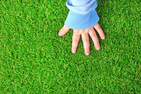 Domo Sports Grass enriched with Pureti – Child hand on artificial grass